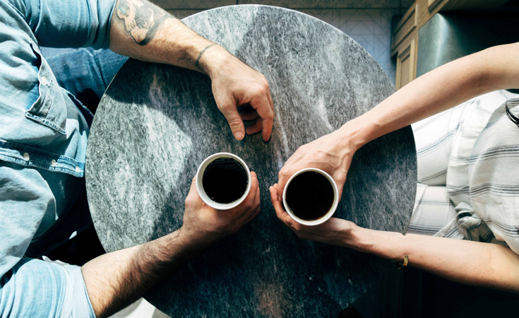 Man and woman sitting at a table talking over coffee – Joshua Ness / Unsplash