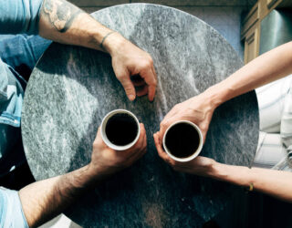 Man and woman sitting at a table talking over coffee – Joshua Ness / Unsplash