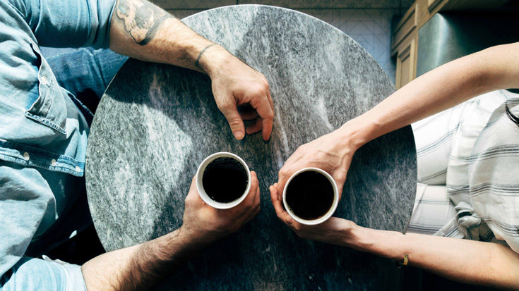Man and woman sitting at a table talking over coffee – Joshua Ness / Unsplash
