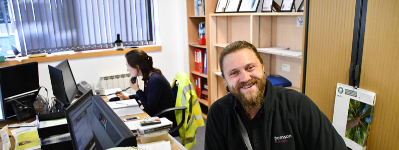 Project Manager Wulf smiling at his desk at Thomson headquarters in Guildford